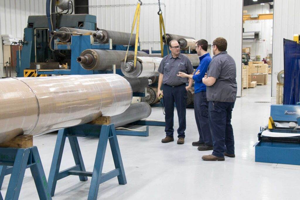 Workers discussing near industrial machinery in factory.